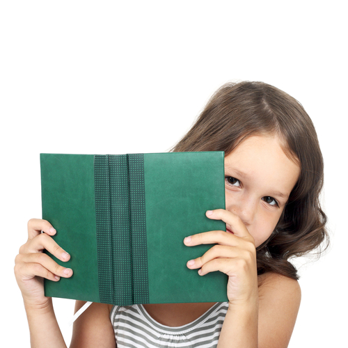 Little girl peeking out from behind a book